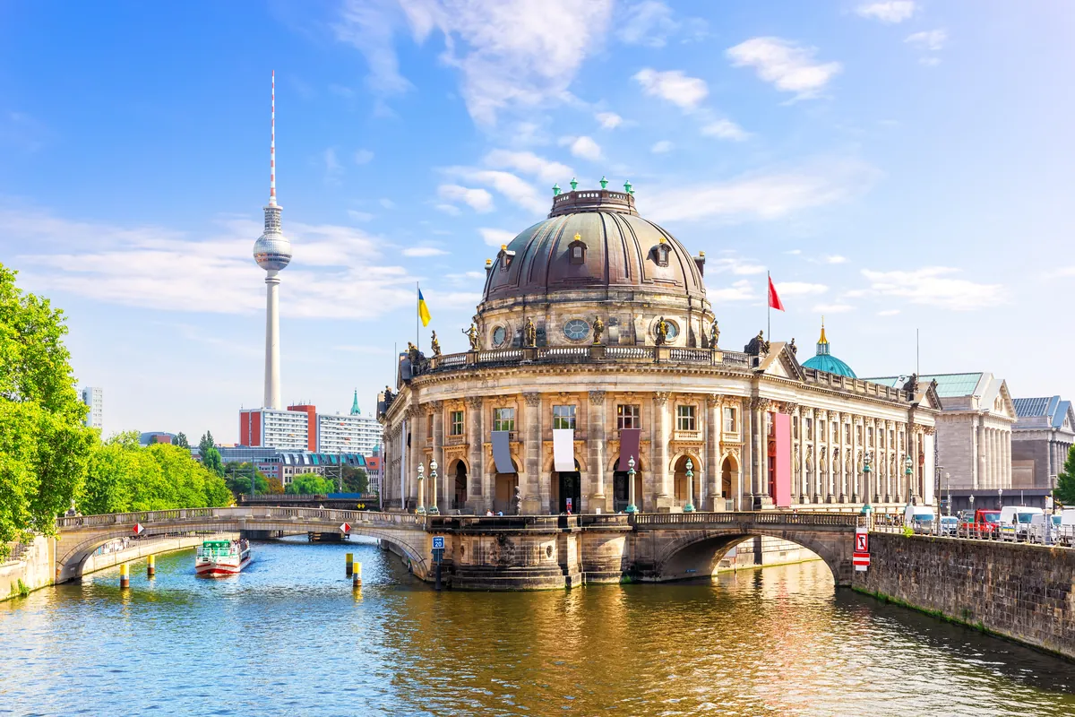 Das Bode-Museum an der Spitze der Museumsinsel in Berlin mit der Spree, einem kleinen Ausflugsboot und dem Fernsehturm an einem sonnigen Tag