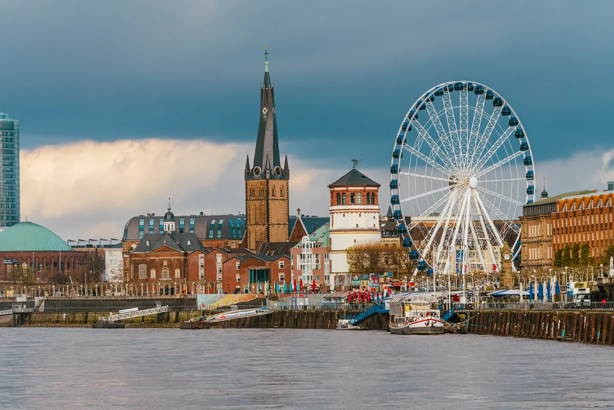 Düsseldorfs Altstadt am Rhein mit dem Turm von St. Lambertus und dem Schlossturm unter dramatischem Himmel