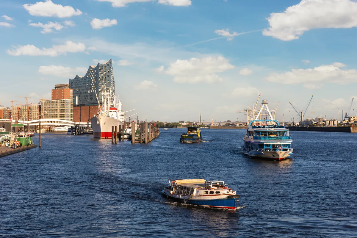 Hafenfähren auf der Elbe in Hamburg, dahinter die Elbphilharmonie und der Hafen