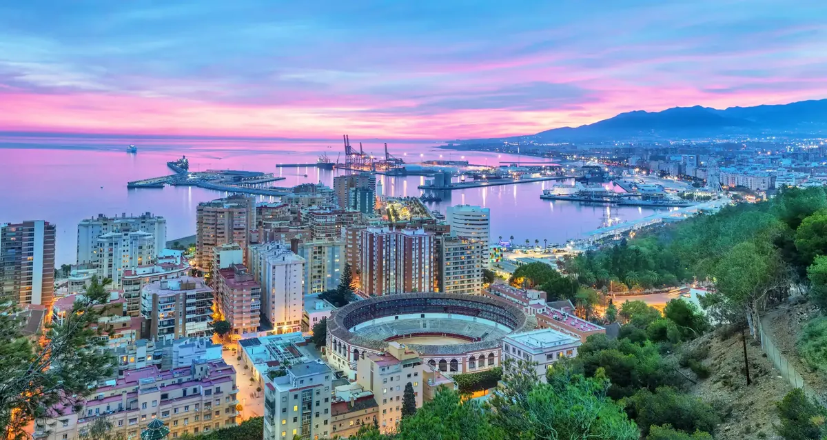 Málaga in der Dämmerung unter rosa Himmel, die Stierkampfarena, der Hafen und die Küste Richtung Osten